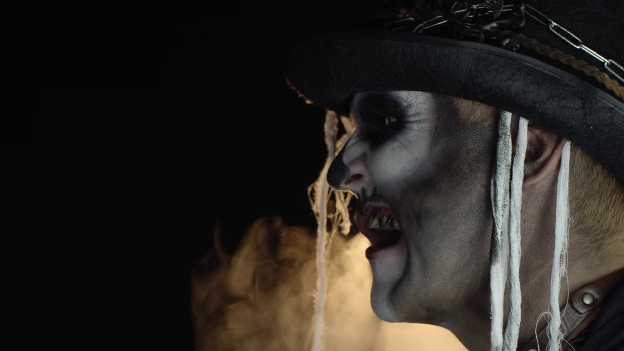 Uomo folle con orribile trucco da scheletro di Halloween che fa smorfie, mostra la lingua, cercando di spaventare.