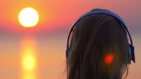 girl listening to music and looking at sunset scene