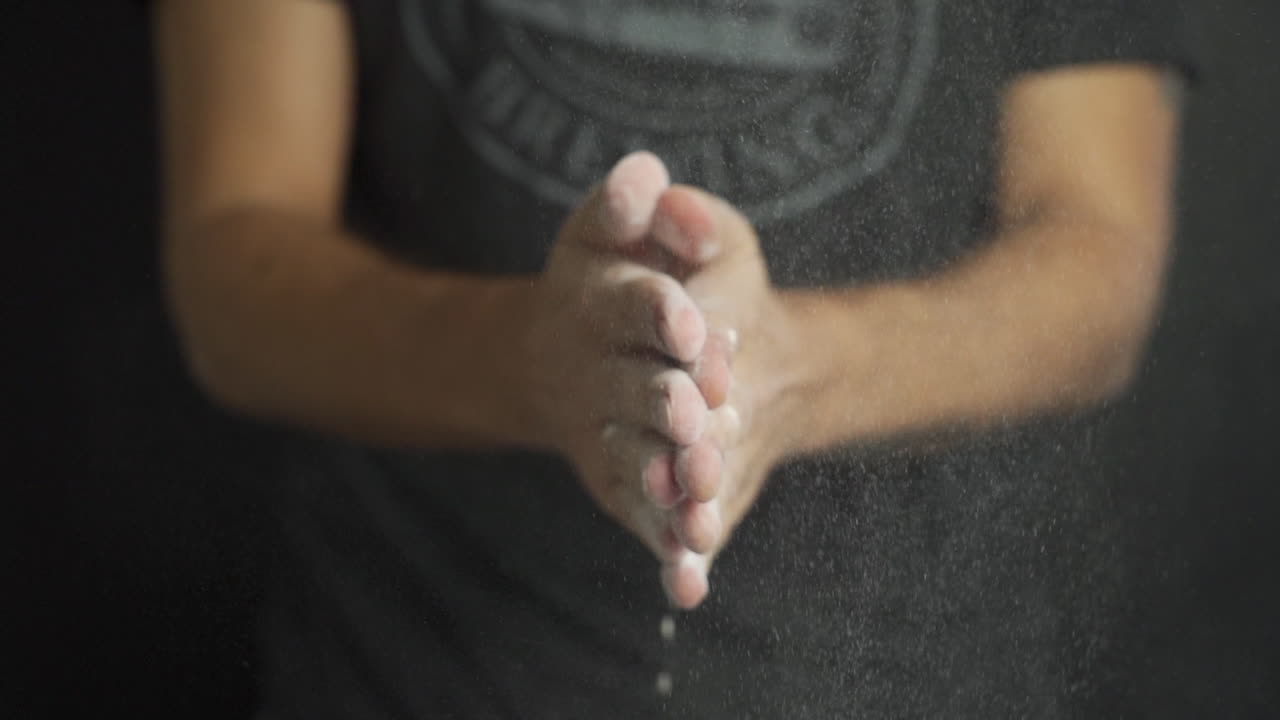 Slow motion of a Baker with flour in his hands while clapping and flour particles are released in the air, cinematic shot