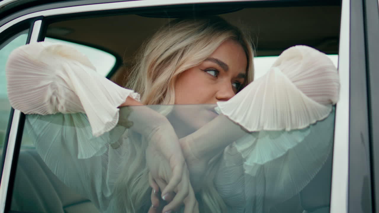 Girl looking car window close up. Relaxed young blonde model posing in retro car