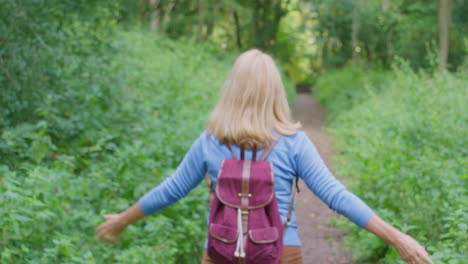 mature couple on hike in countryside walking towards each other along path through forest