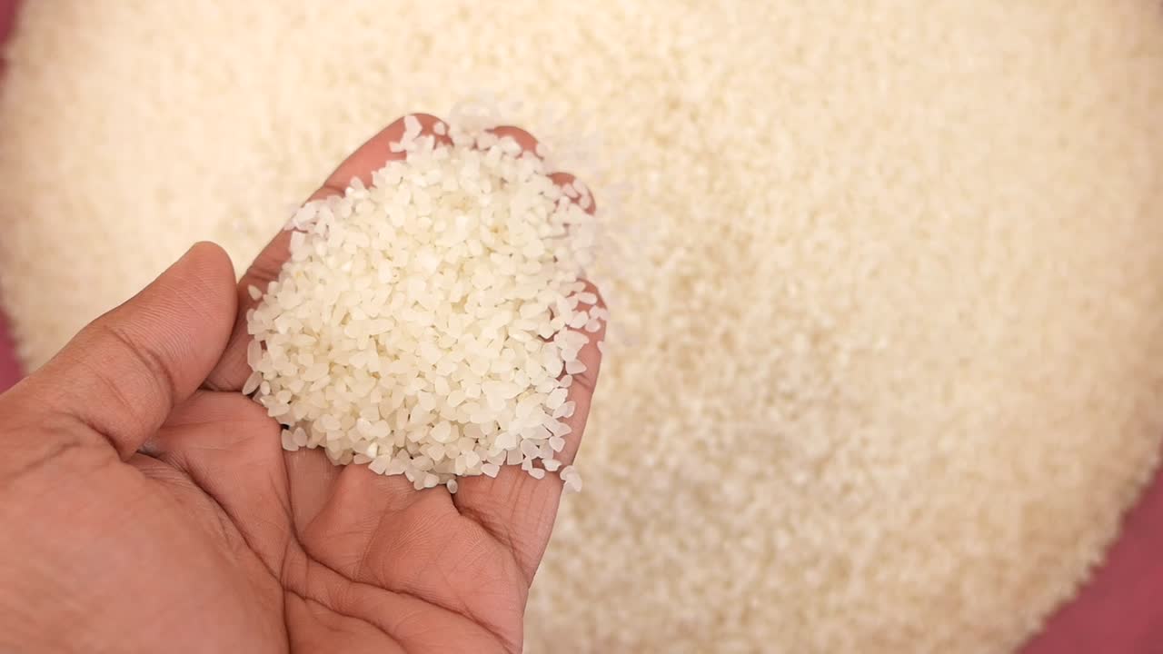 Primo piano di mano che versa chicchi di riso bianco