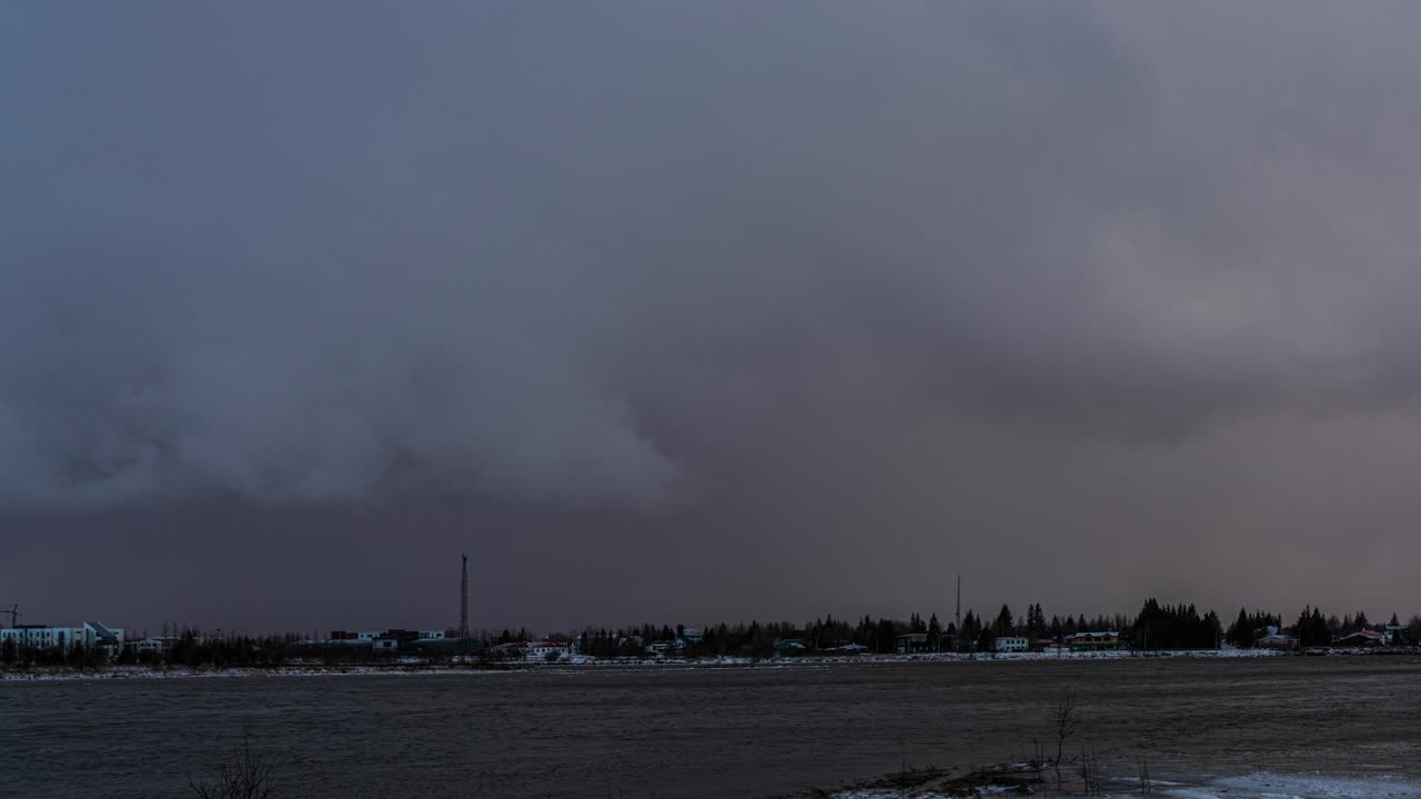 Time lapse storm clouds passing over a town in Iceland, from dark and gloomy to sunny again