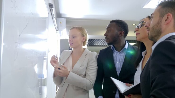 Riunione del team aziendale intorno a una lavagna bianca