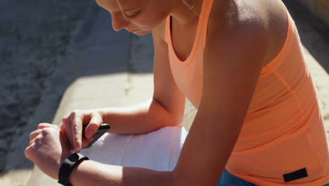 Side-view-of-Caucasian-female-athlete-using-smartwatch-at-sports-venue-4k