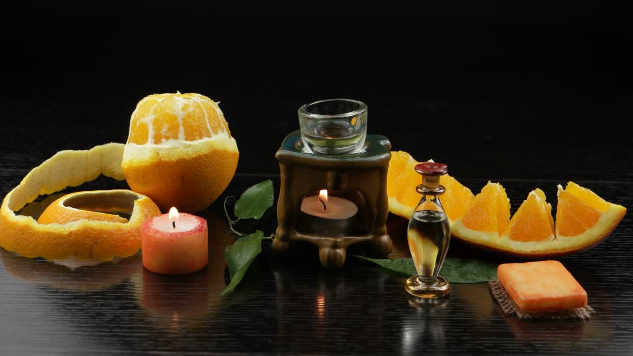 aromaterapia con aceite de naranja. lámpara de aroma, fruta de naranya, jabón de naranje, botellas con aceite de naranja en una mesa de madera negra