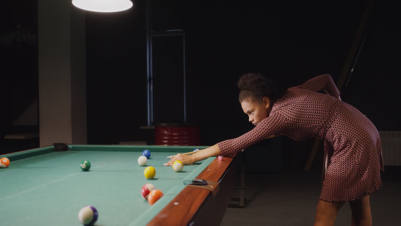 mujer jugando al billar en una habitación oscura