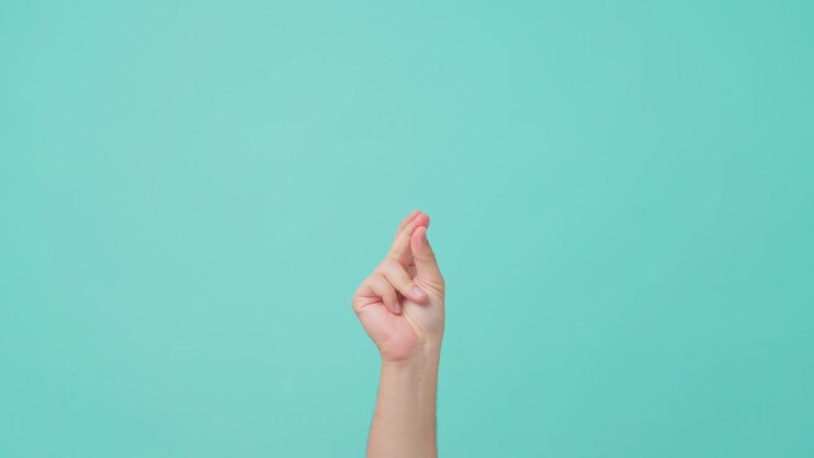 близкий снимок человеческой руки, поднимающей руку, с жестом сжатия пальца. человек, сжавающий палец, пытаясь сделать звук, чтобы привлечь внимание людей. виден в изолированном синем экране на заднем плане.