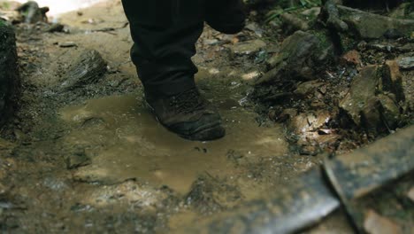 hiking boots shoes close up during an outdoor hike, trekking footwear stepping in mud, slow motion