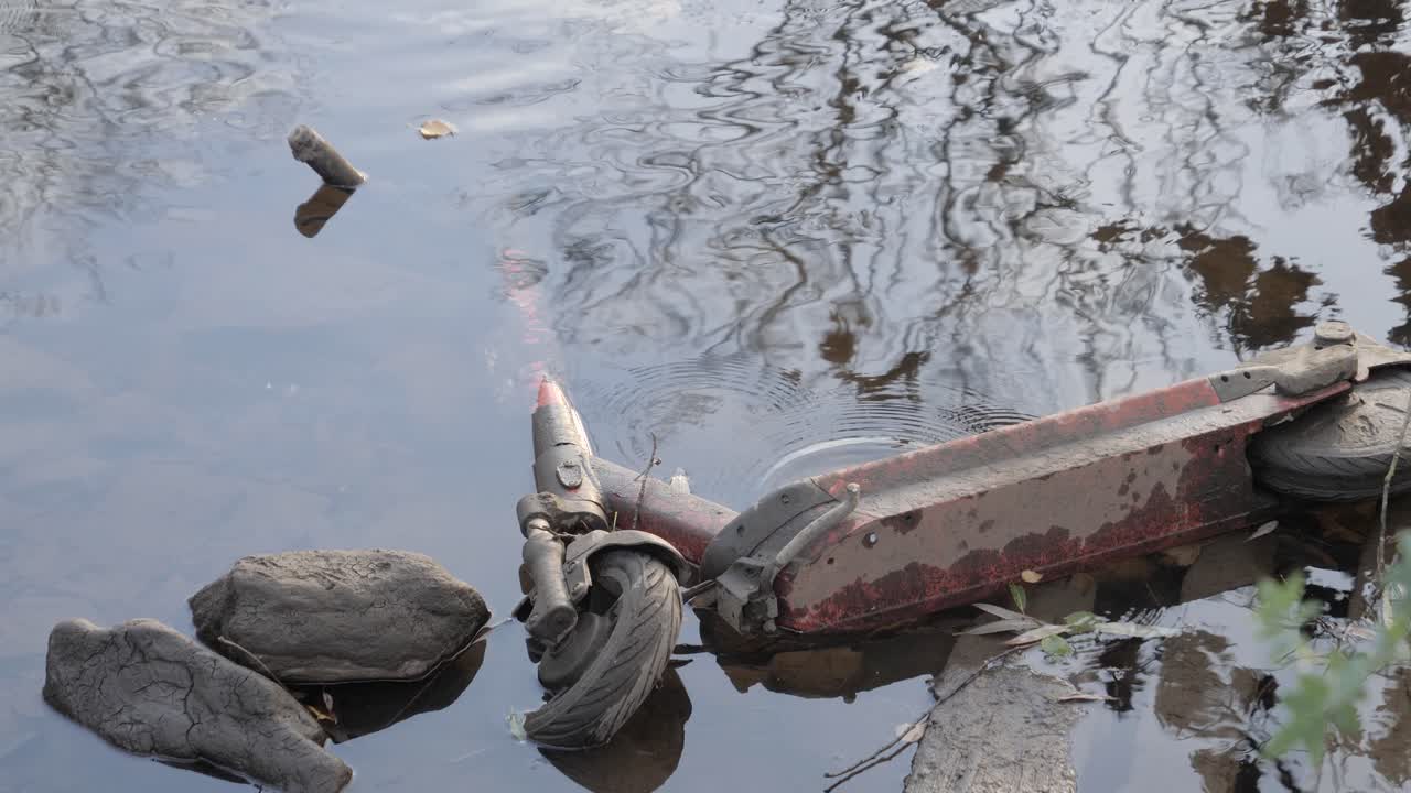 Abandoned scooter in a serene river, nature meets urban decay
