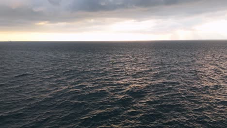 Sunset-over-the-ocean-in-Nervi,-Genoa-with-calm-waves-and-a-distant-sailboat,-a-serene-seascape