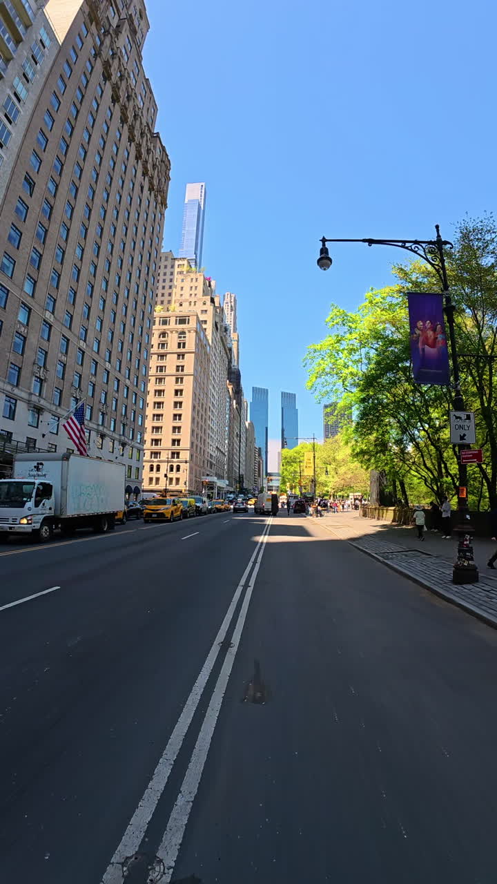 New York, USA, 2 August 2025: Central Park West street morning. Central Park West opens wide with bright trees and tall towers around