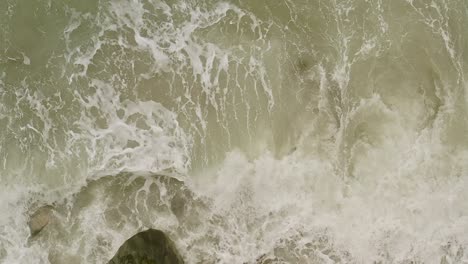 aerial top down view of slow-motion waves over rocks at banbanon beach, philippines
