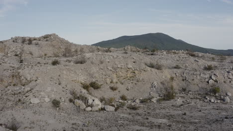 fly over the abandoned quarry on top of the mountain, with opening view of the green mountain ridge in the distance on a clear sunny day