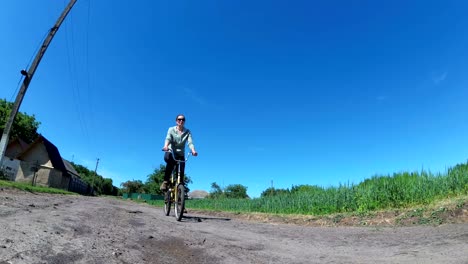 young woman riding vintage bicycle along a rural road in a village