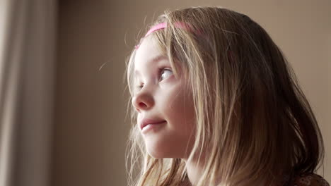retrato iluminado por el sol de una hermosa niña mirando por la ventana