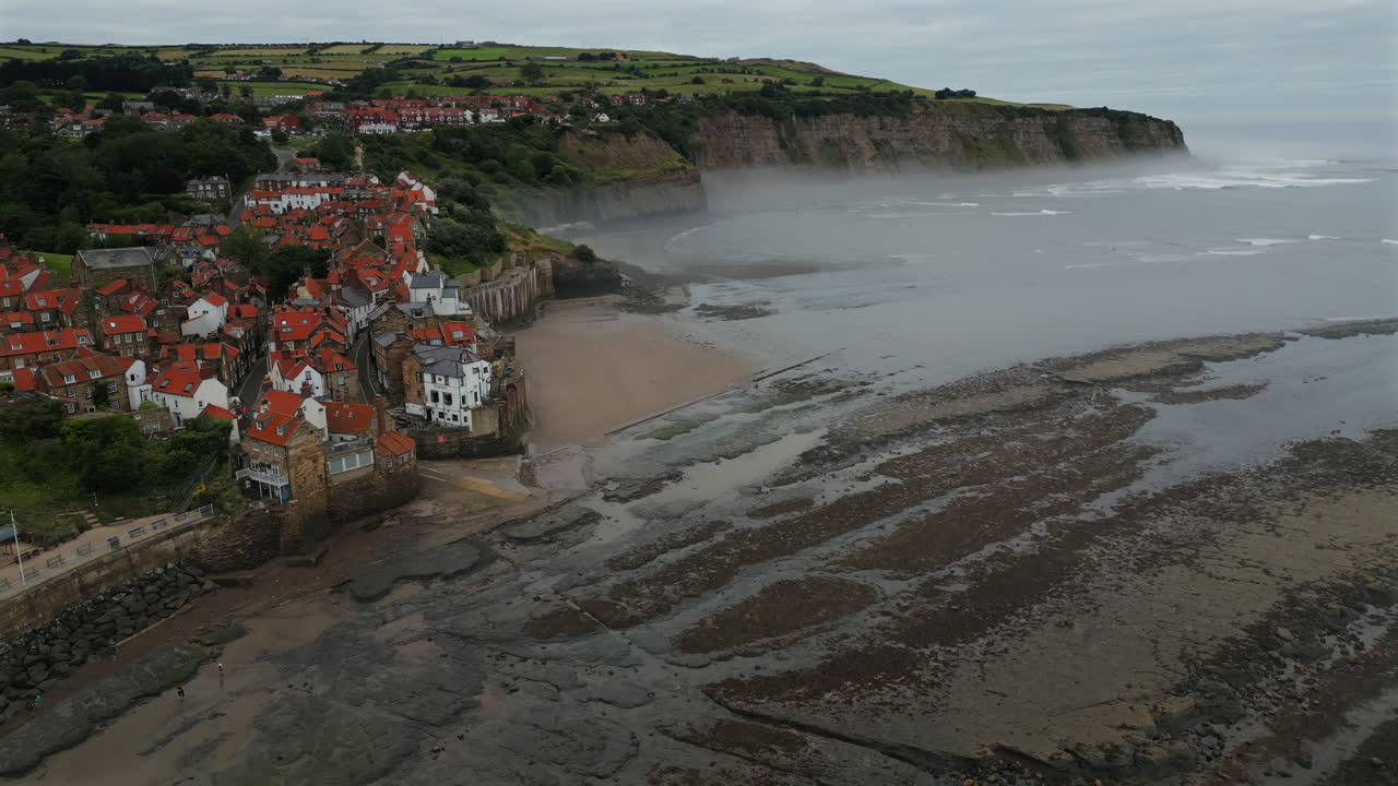 Establishing Aerial Drone Shot of Robin Hoods Bay on Misty Morning at low Tide