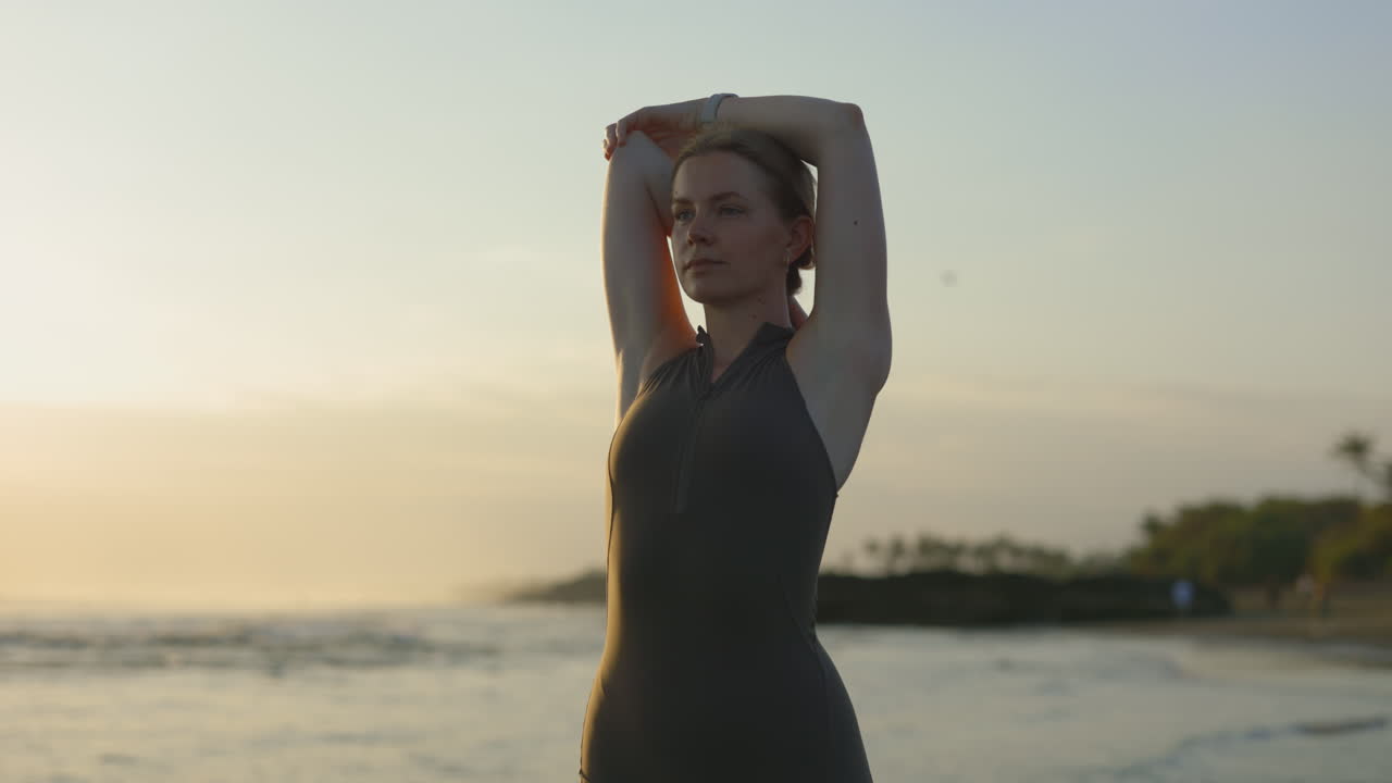 Woman stretching on beach at sunrise