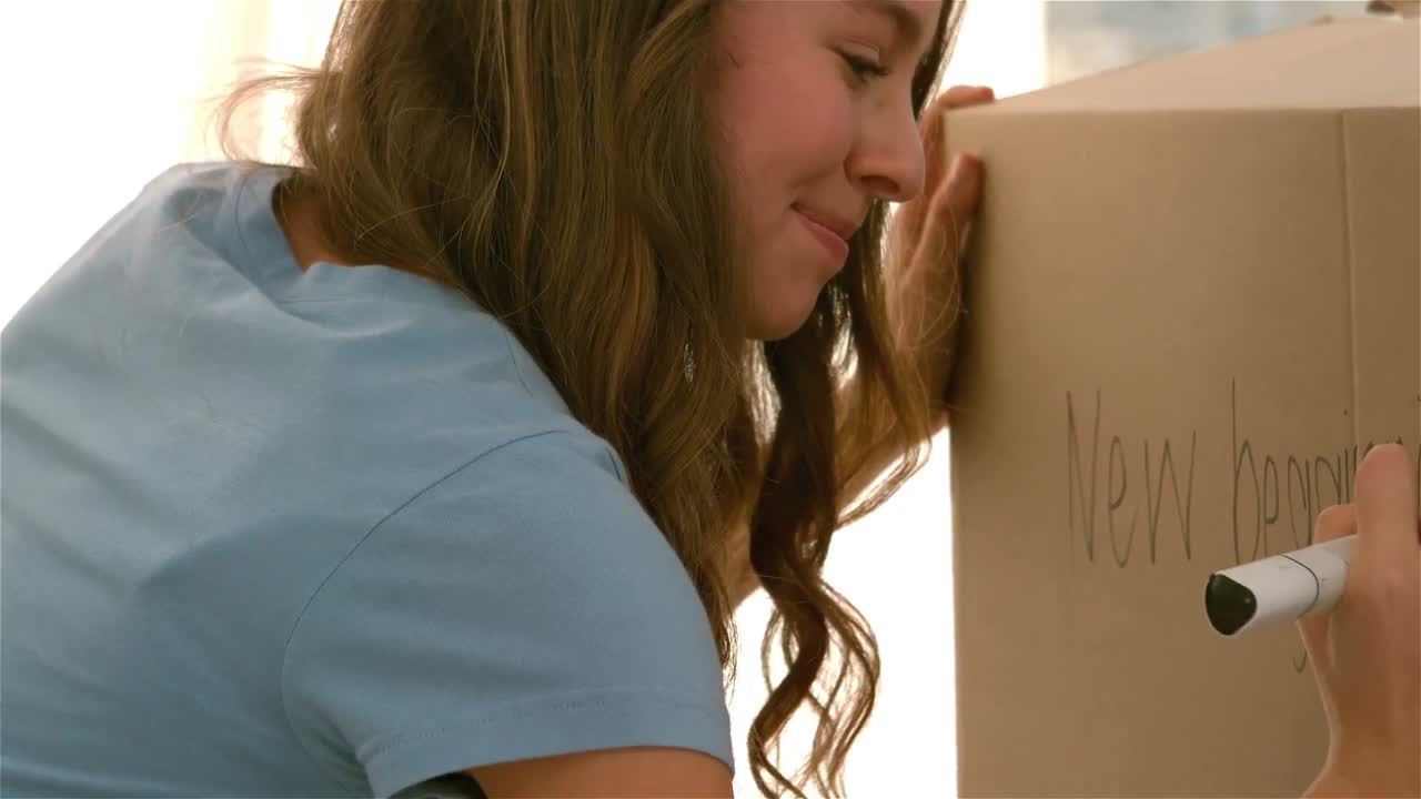 Pretty girl writing 'New begginning' on a box