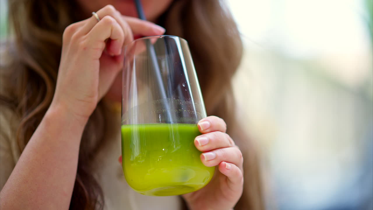 Woman drinking green matcha cocktail, at a cafe, outside
