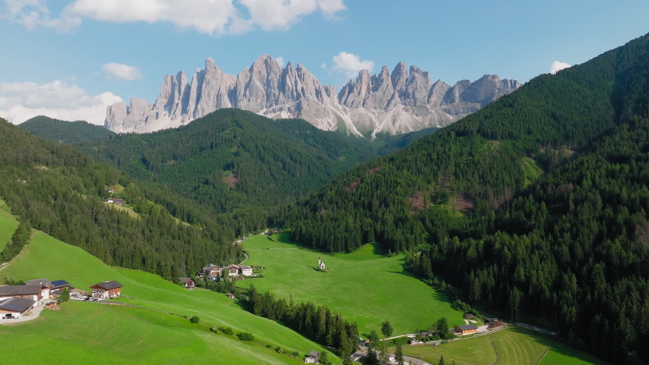 Church of St. John sits beneath dramatic Dolomite range in vivid green alpine valley
