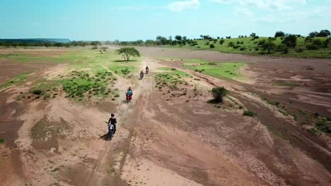 motorcycles riding through african landscape - aerial drone shot