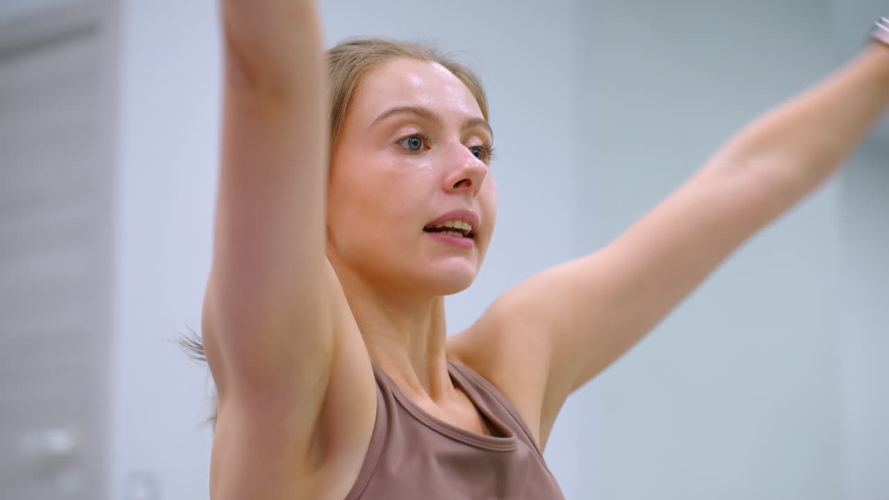 잘 조명 된 체육관에서 머리 위에 저항 밴드를 는 피트니스 세션에 참여하는 여성의 가까운 사진, 대화하고 운동 루틴에 초점을 맞추고