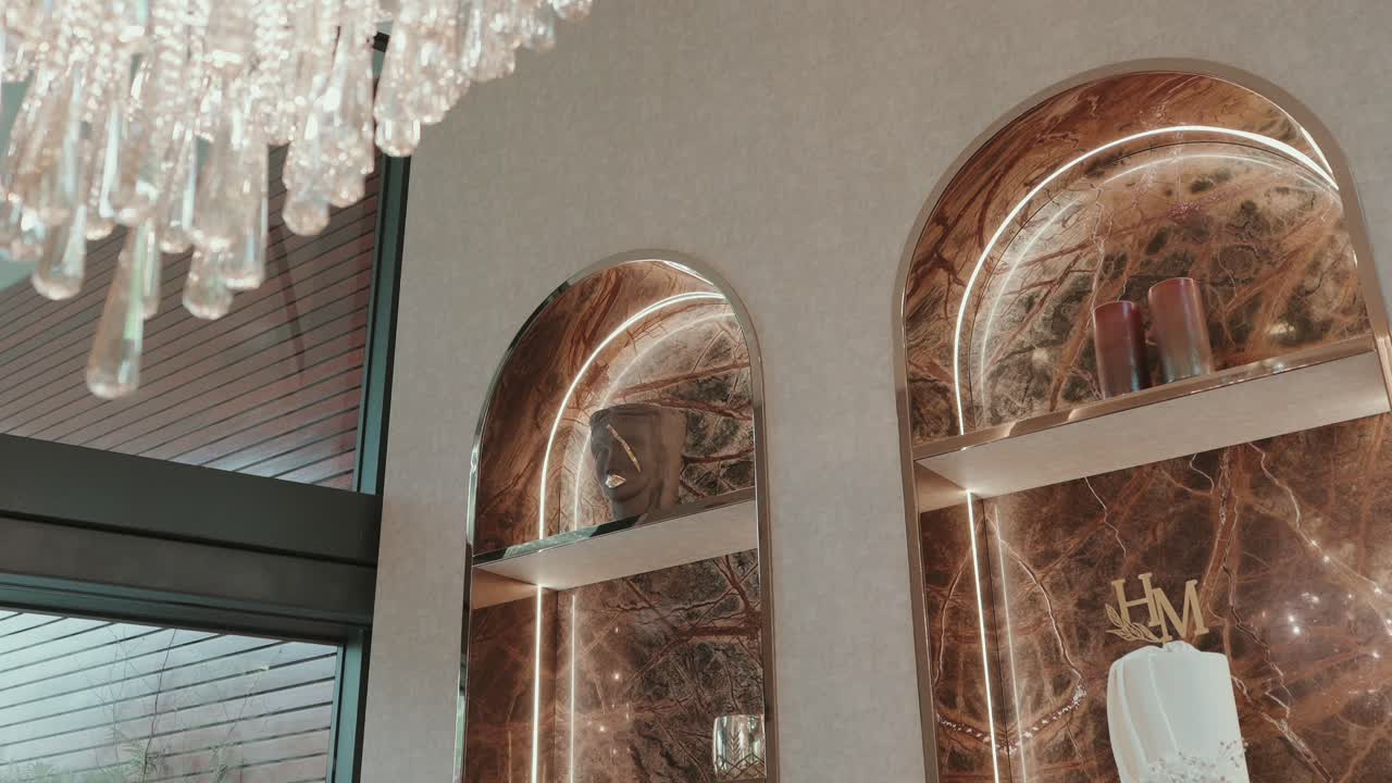 arched marble shelves with decor under chandelier in upscale space