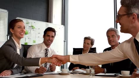 Business-people-looking-at-couple-handshaking