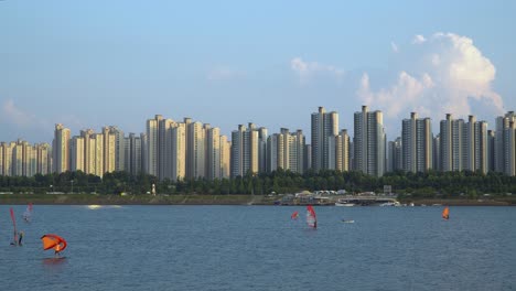 gente haciendo windsurf en el río han al atardecer en un complejo complejo de apartamentos altos, club de surf ttukseom