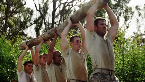 tropas militares que llevan troncos de madera pesados durante una carrera de obstáculos 4k