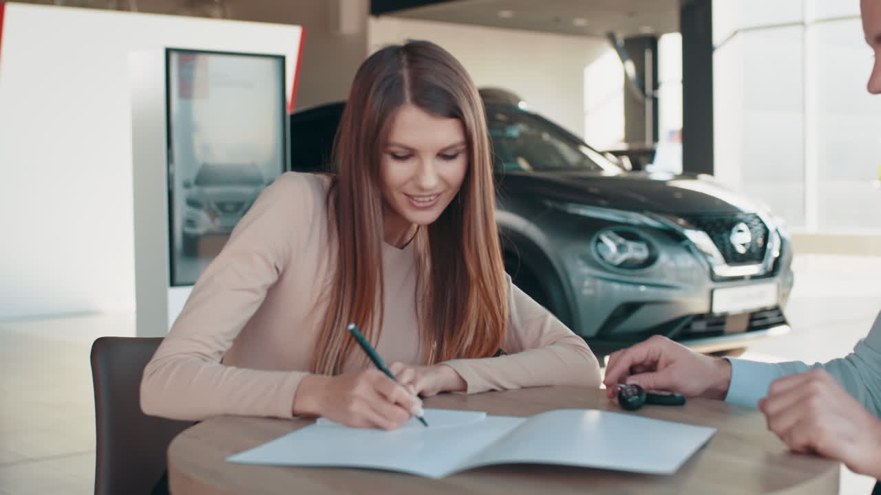 mujer firmando documentos de compra de automóviles en un concesionario