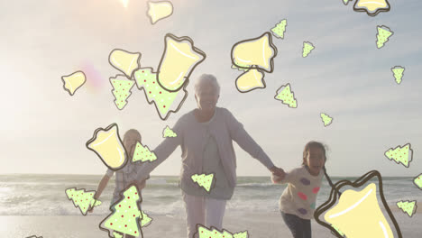 animation of christmas tree and bell icons over biracial family at beach