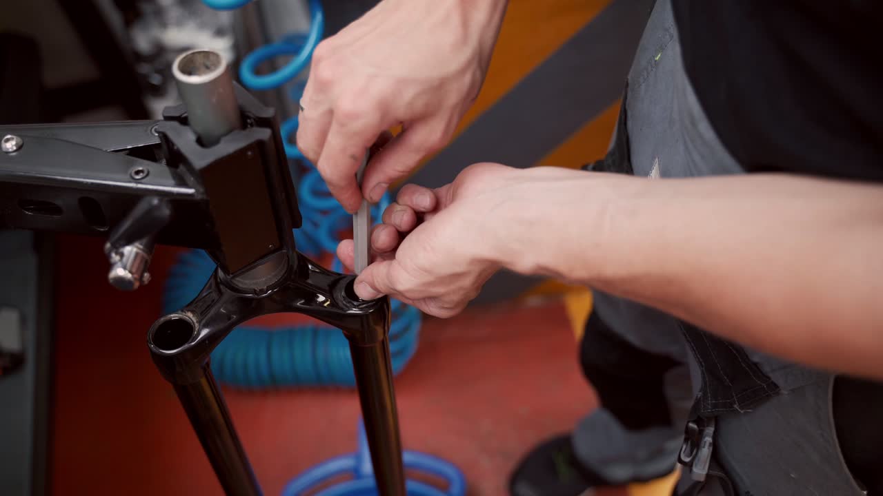 reparador de cultivos desenroscando una horquilla de bicicleta con un destornillador en el taller