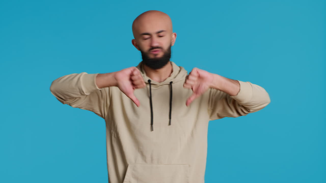 Middle eastern guy showing thumbs down sign on camera