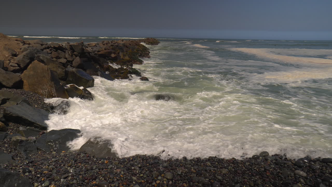 océano golpeando pequeñas rocas en la playa de perú