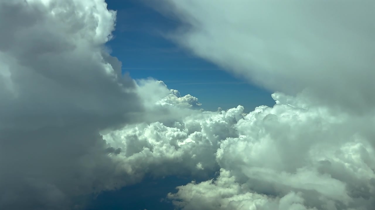 pilot POV flying between towering cumulonimbus strom clouds in a blue sky, doing some turns to avoid turbulence. 120000m high.