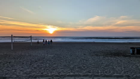 pan a través de la playa de manhattan al atardecer, los turistas disfrutan del encanto costero y los tonos dorados