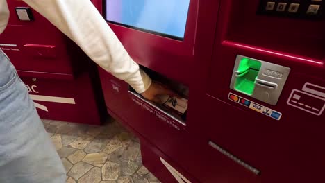 person retrieves ticket from vending machine