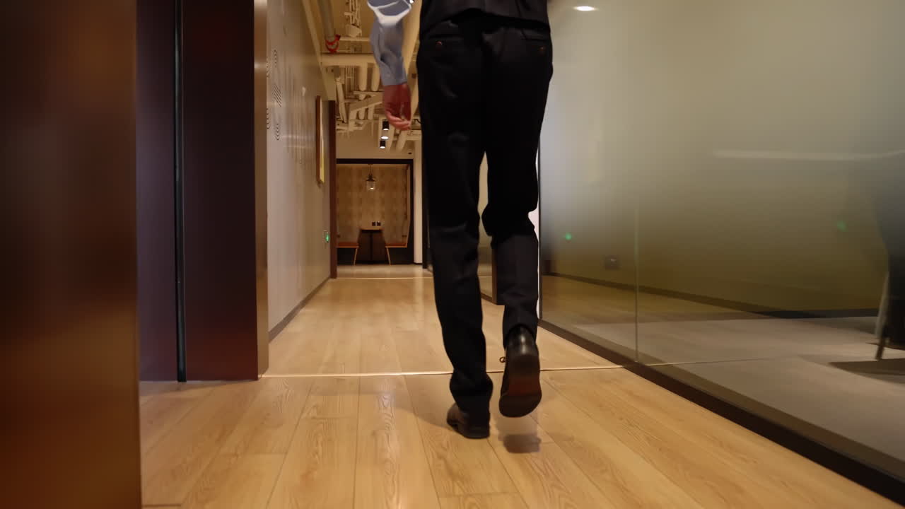 A businessman in a formal suit walking along corridor of leading company, spacious office corridor with glass windows, symbolizing journey towards success and opportunities in a corporate environment