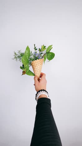 hand holding ice cream cone with flowers and plants