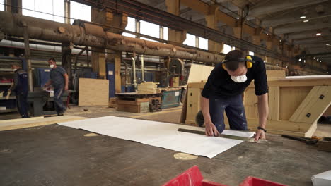 woodworker marking plan on a factory floor