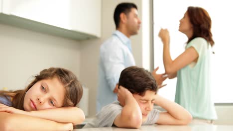 upset siblings covering their ears while their parents fight