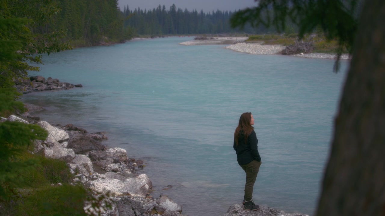 Woman standing on the rock in the river and looking at the landscape
