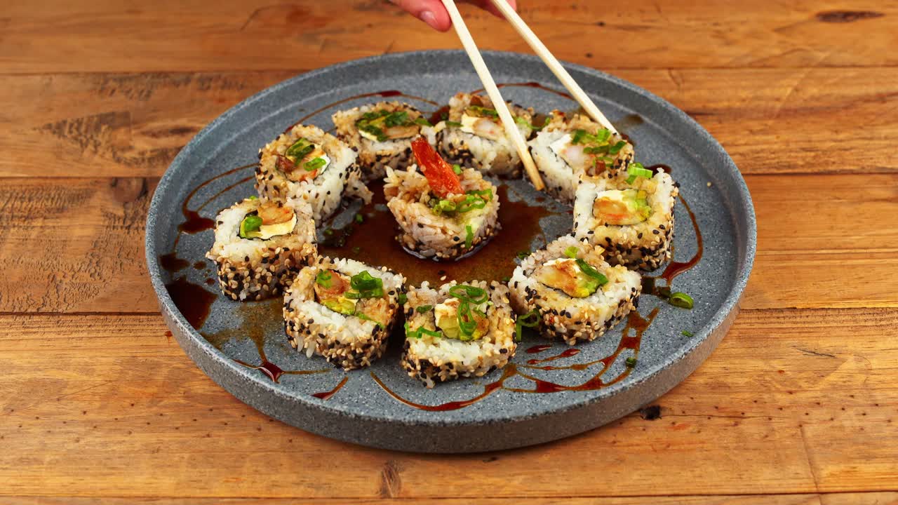 primer plano de un plato de sushi sumergido en salsa de anguila y tomado con