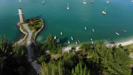 aerial til down view of a lighthouse and luxury yachts with turquoise ocean 4k