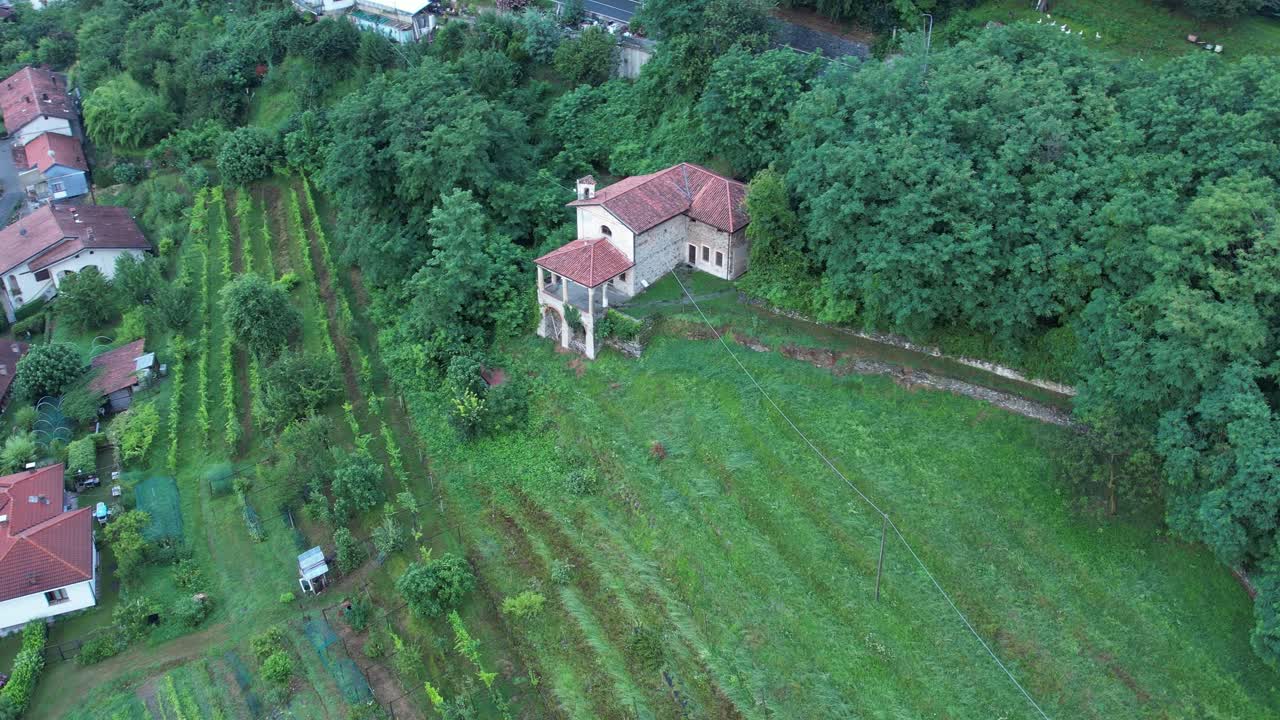 Slow motion drone shot captures the historic heart of Colleretto Giacosa with its iconic red-tiled rooftops and surrounding cultivated fields in the Piedmont region, Italy
