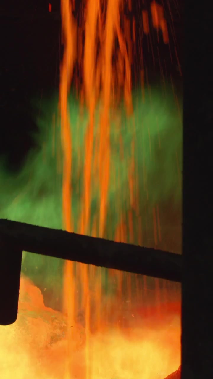 Steel Stream Pouring Into Vat With Green Flame And Gas Plume, Intense Glow, Spout And Pipe Silhouette, High