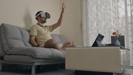 man operating digital interface with vr headset while sitting on couch in living room