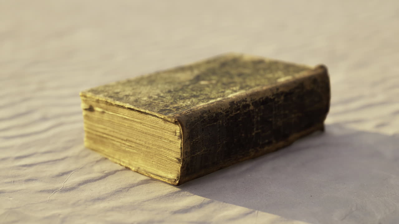 Старинная книга в кожаном переплете лежит на текстурированной поверхности в условиях мягкого освещения